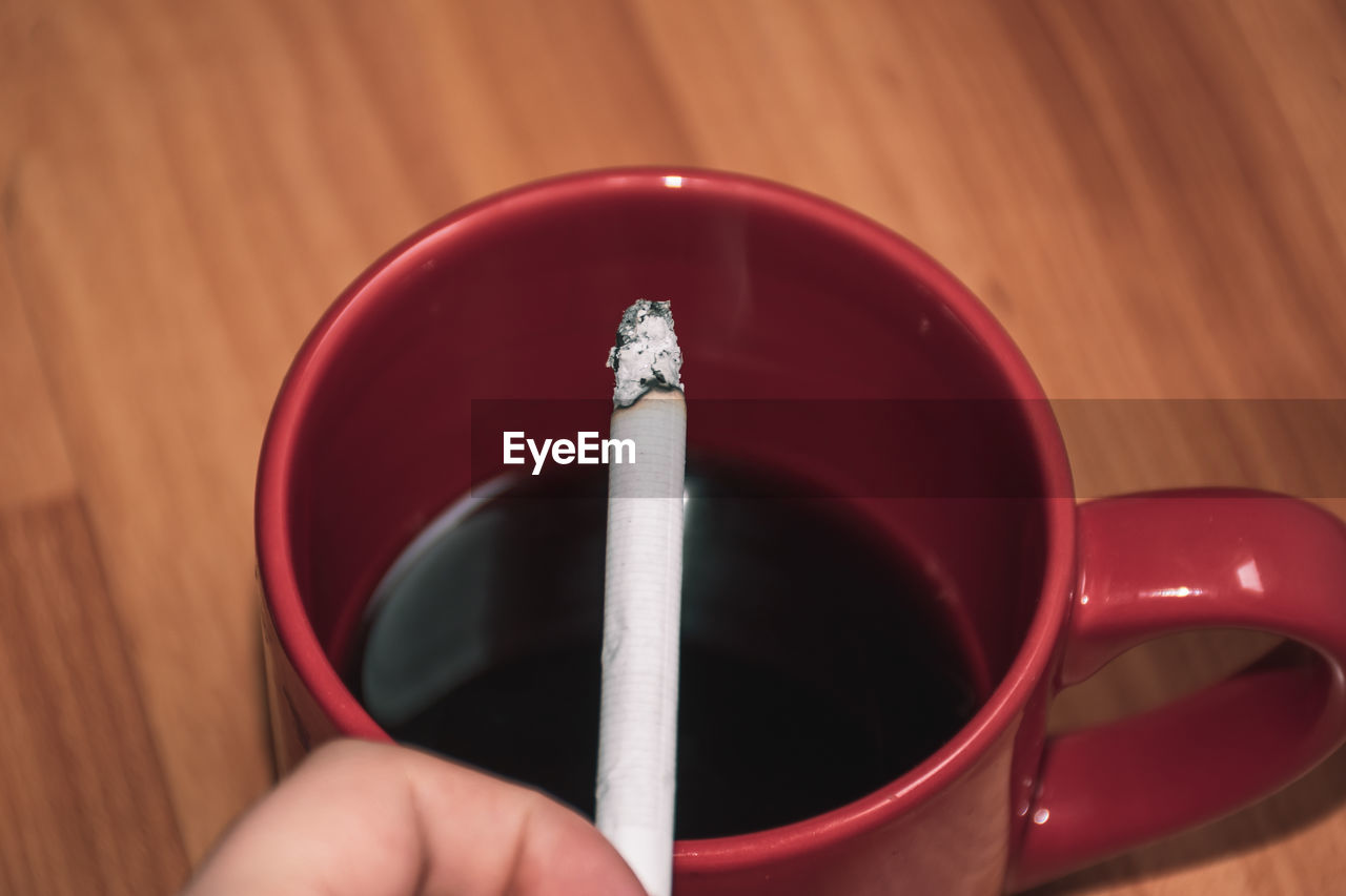 CLOSE-UP OF PERSON HAND HOLDING CIGARETTE WITH EYEGLASSES
