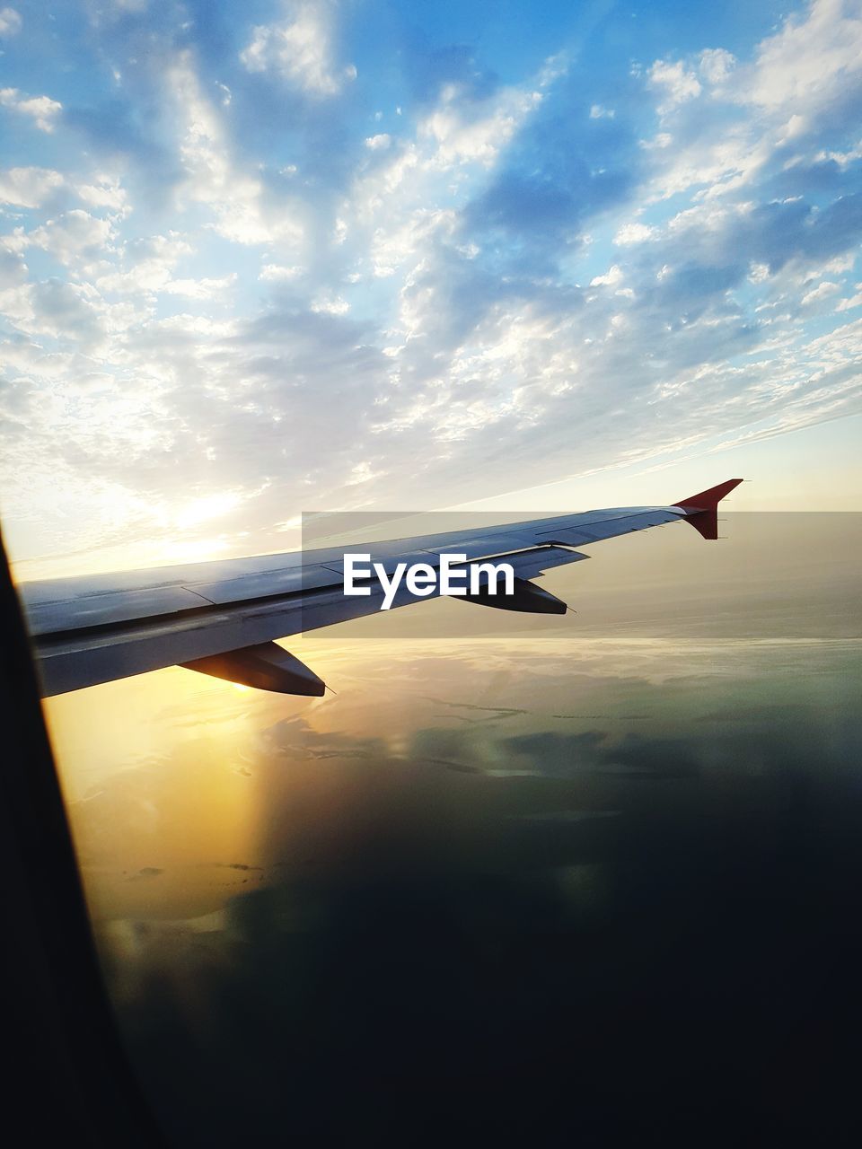 AIRPLANE FLYING OVER SILHOUETTE LANDSCAPE AGAINST SKY