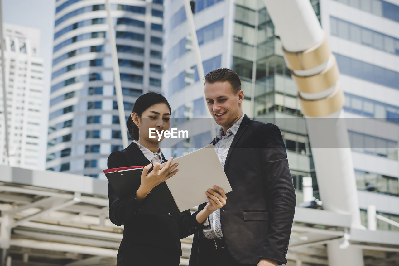 Low angle view of business people discussing while standing against building