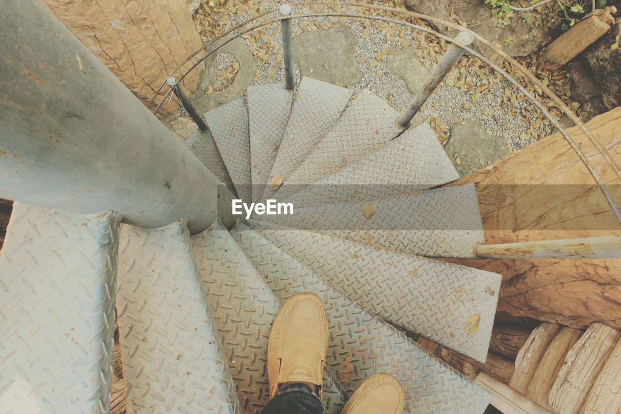 Low section of man standing on spiral staircase