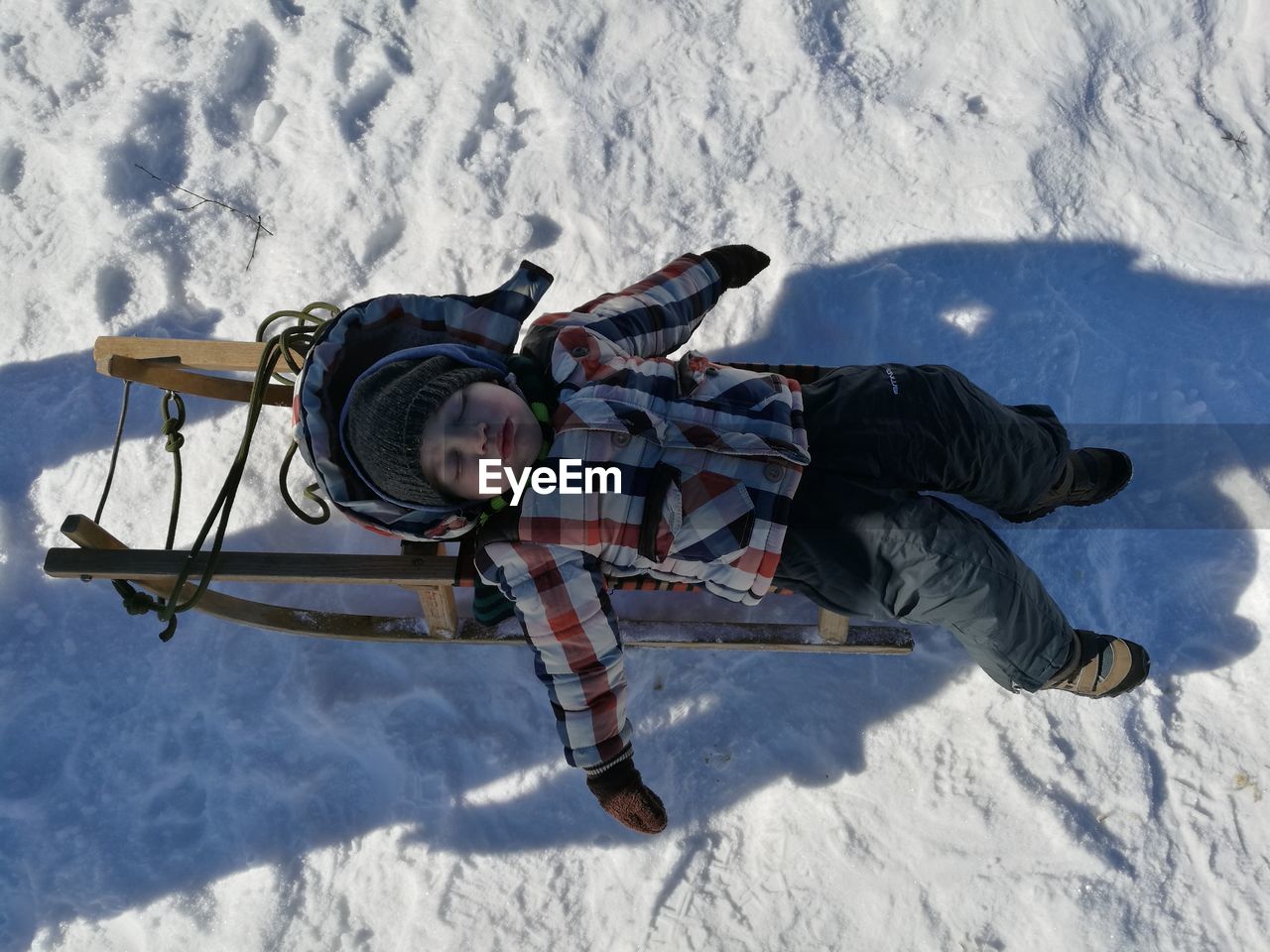 High angle view of boy sleeping on sled during winter