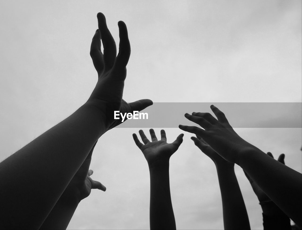 Cropped hands of people against sky