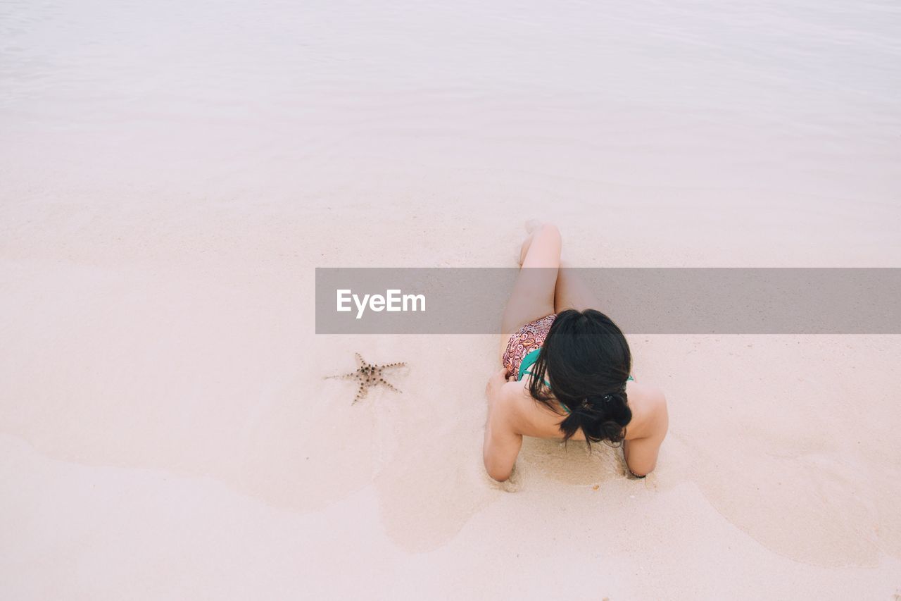 High angle view of young woman lying on the beach