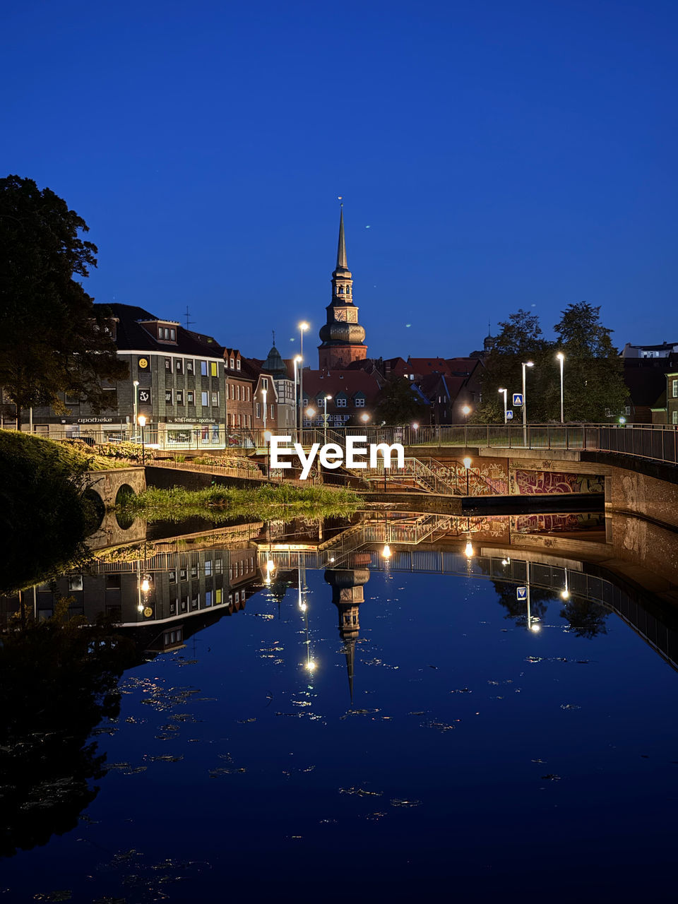 Reflection of buildings, streetlights and stars in water of the channel in the city