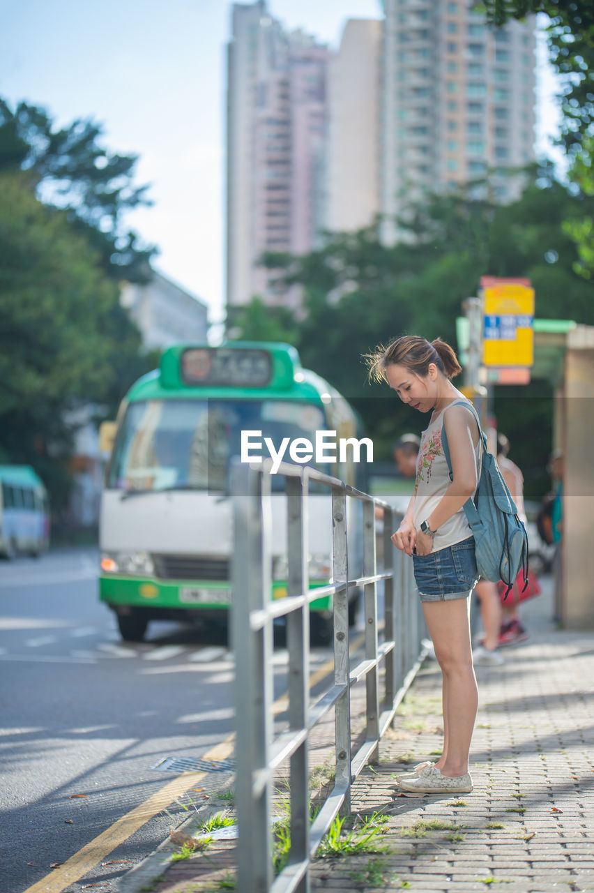 Woman standing on footpath in city