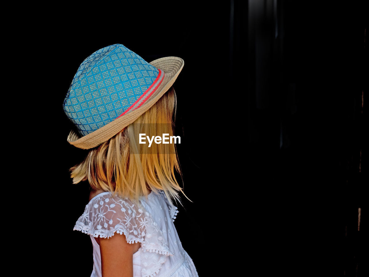 MIDSECTION OF WOMAN WEARING HAT AGAINST BLACK BACKGROUND