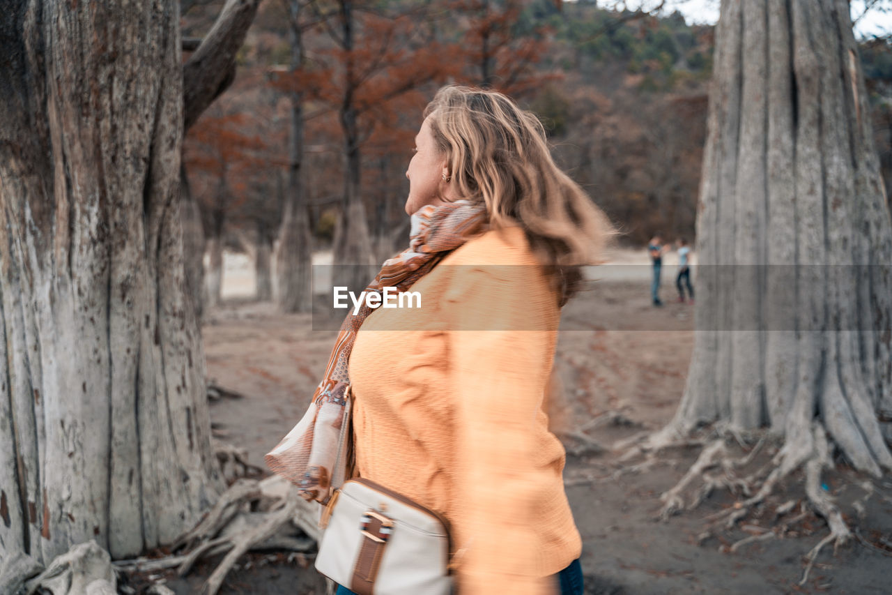 Side view of woman standing on tree trunk