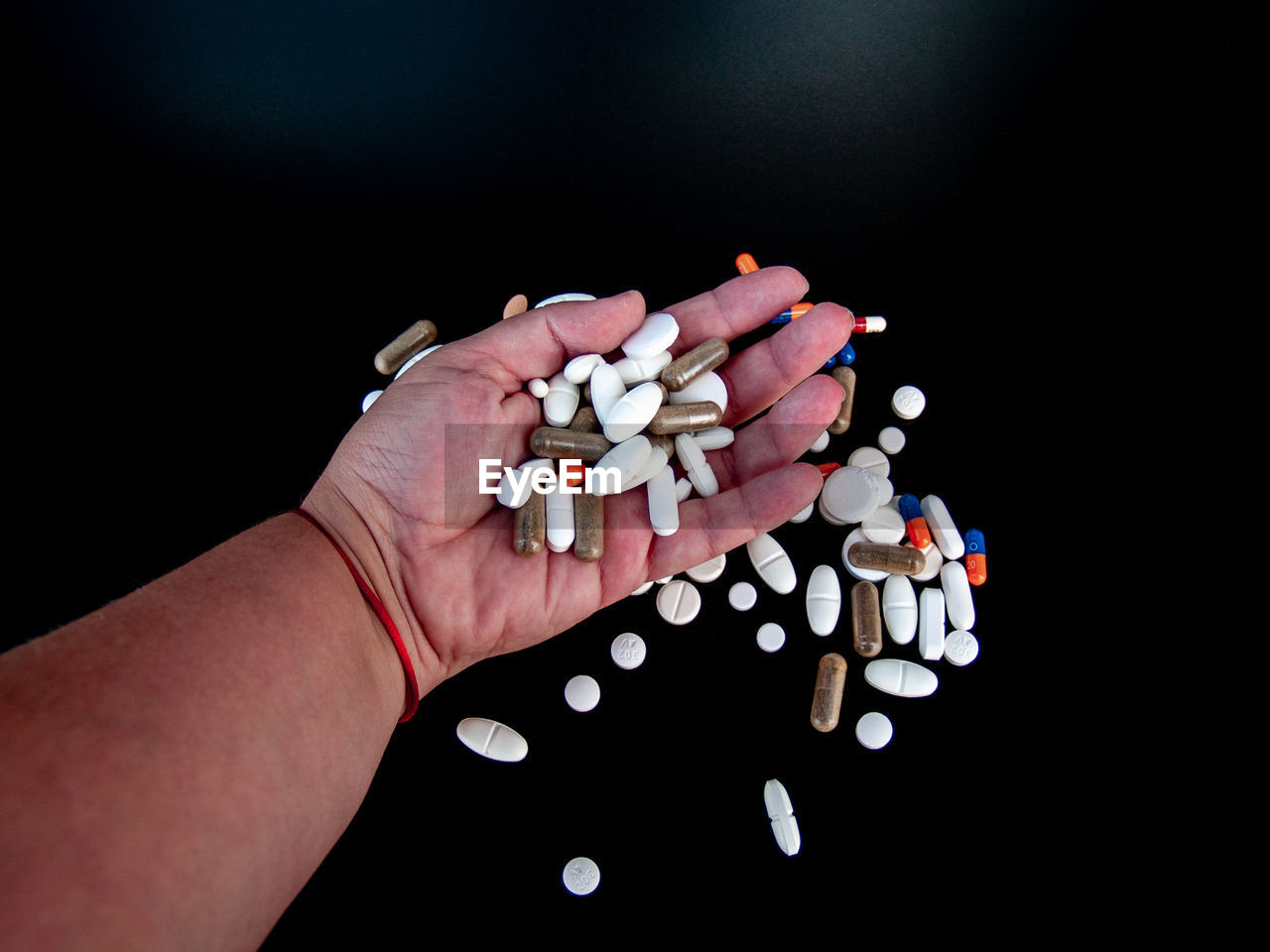 Cropped hand holding medicines over black background