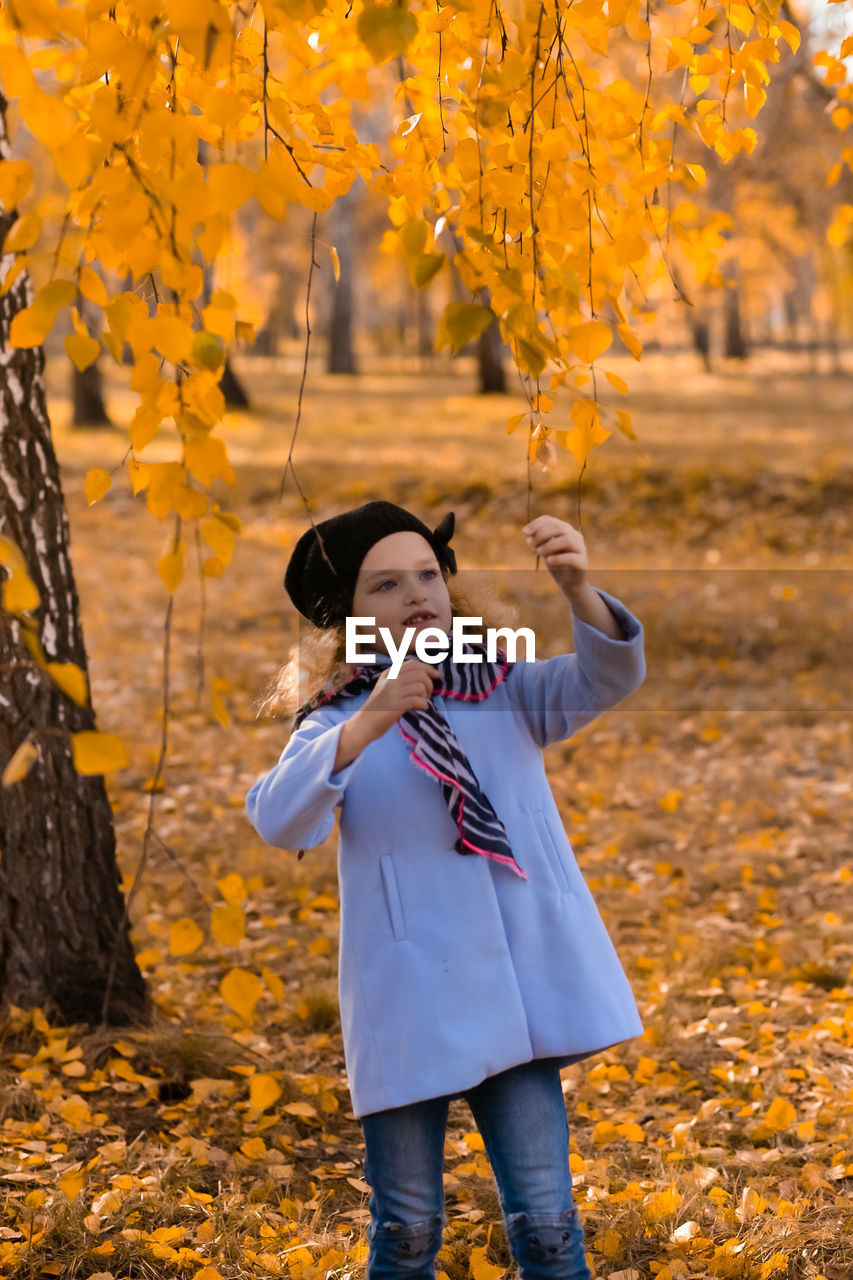 Close-up of cute girl holding branch during autumn