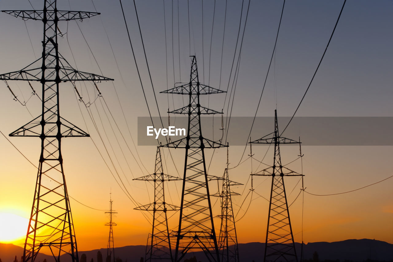 low angle view of electricity pylon against sky at sunset