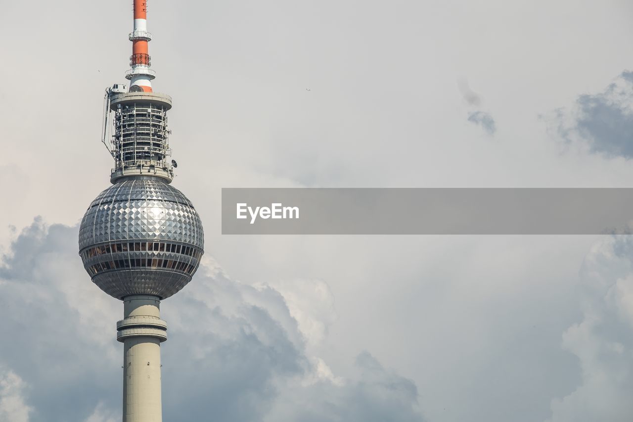 Low angle view of fernsehturm against cloudy sky