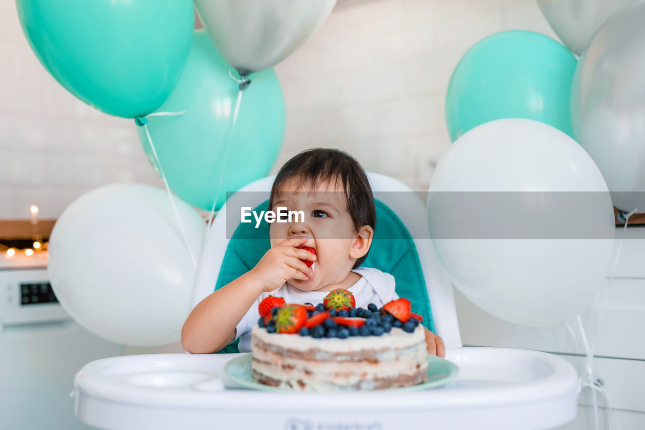 PORTRAIT OF HAPPY BOY WITH BALLOONS IN CONTAINER