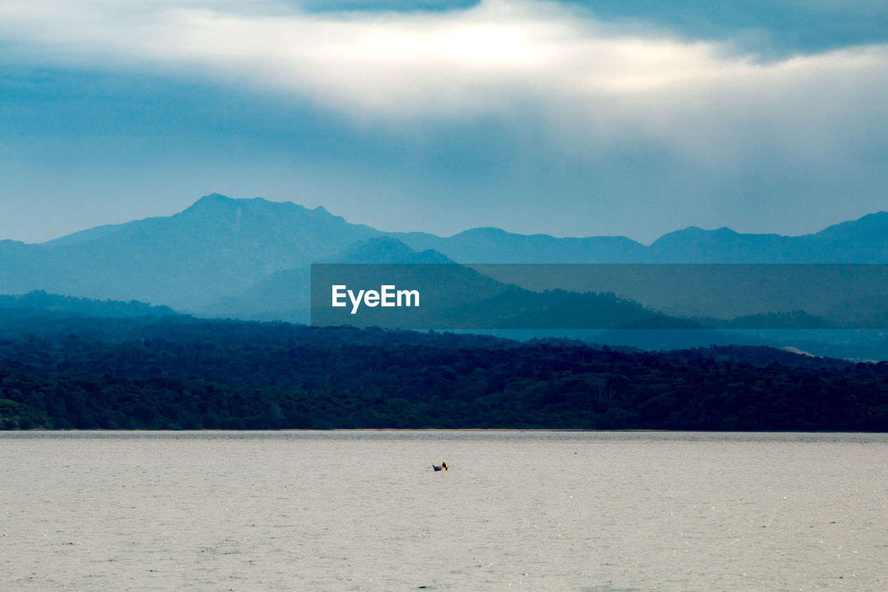 Scenic view of sea and mountains against sky