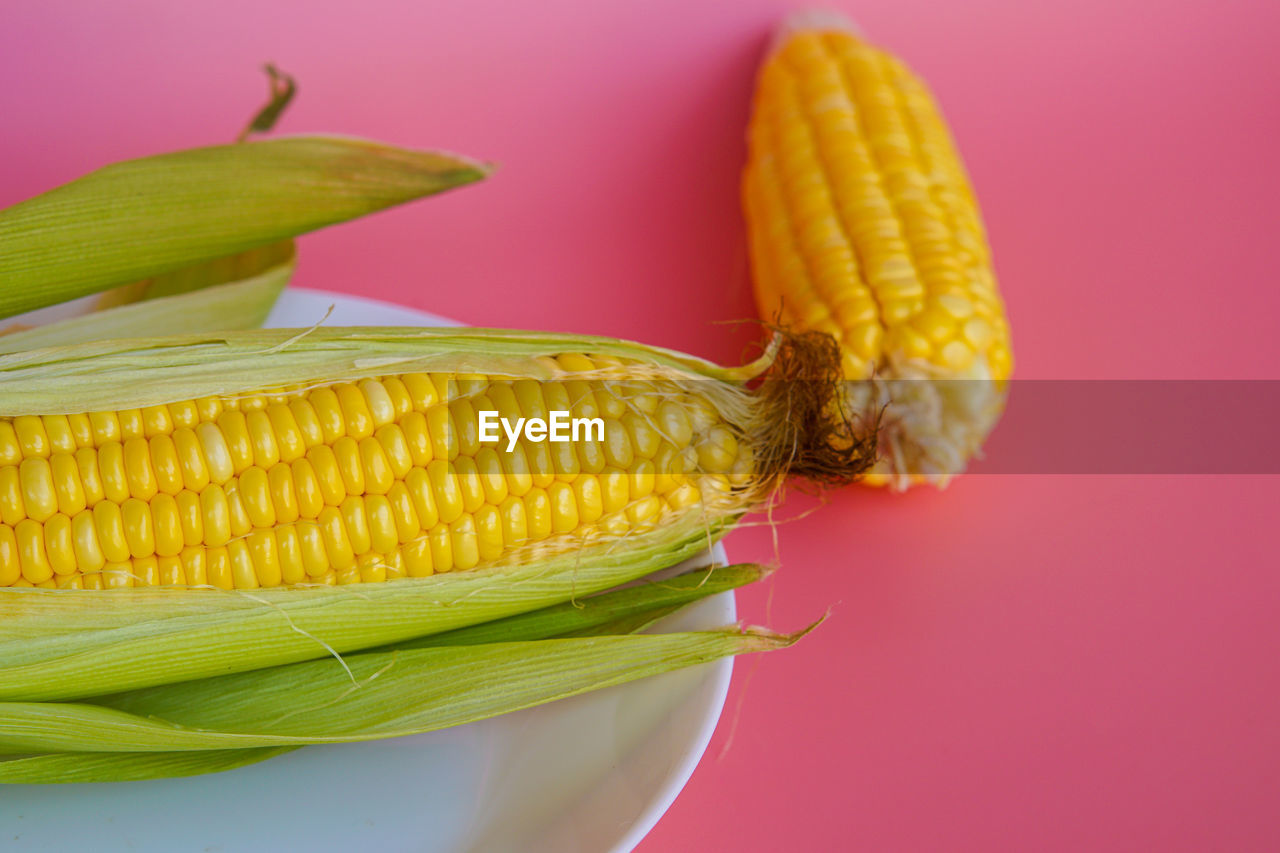 Close-up of corn on table against colored background