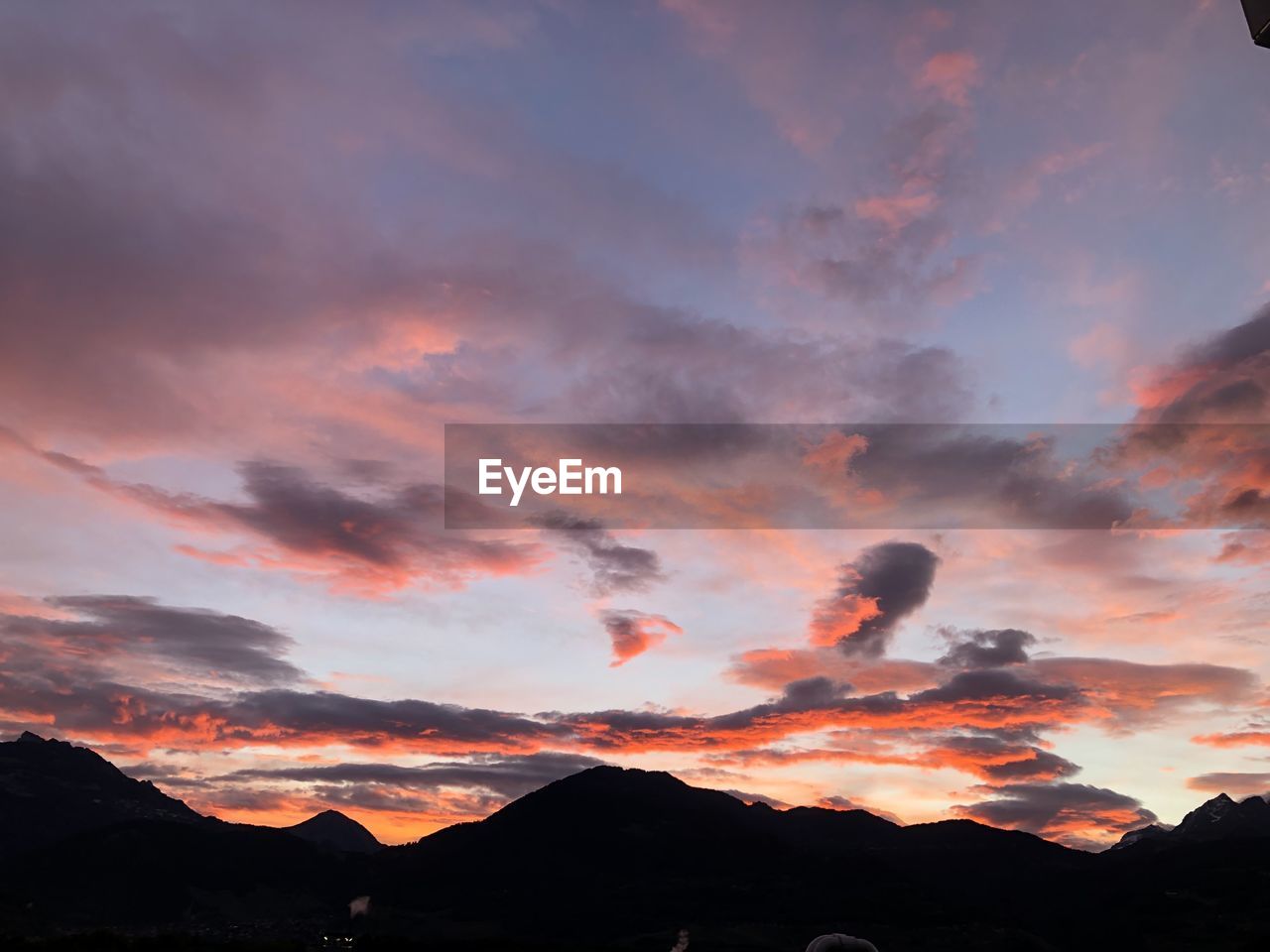SCENIC VIEW OF SILHOUETTE MOUNTAINS AGAINST DRAMATIC SKY