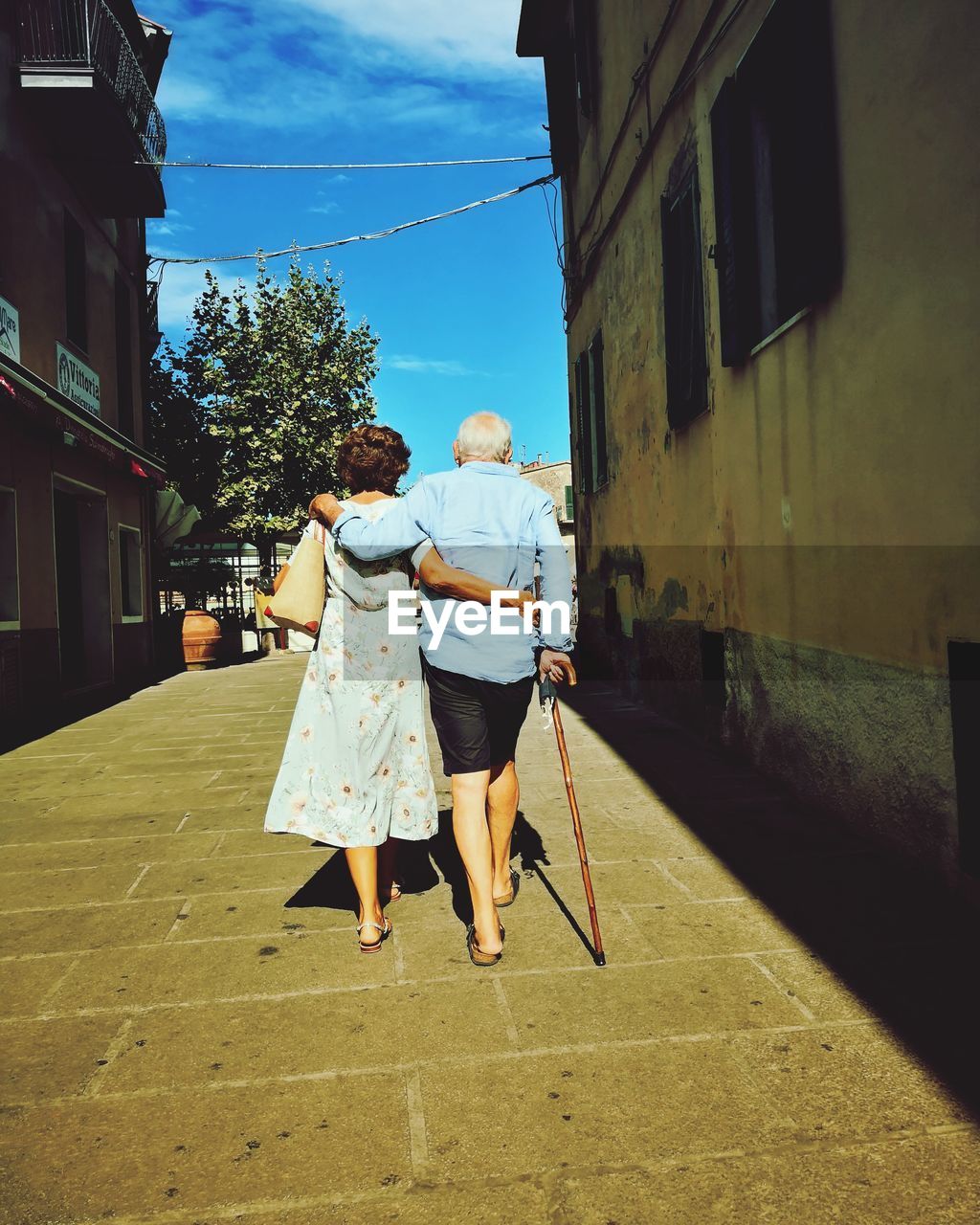 Rear view of senior couple walking on street amidst buildings