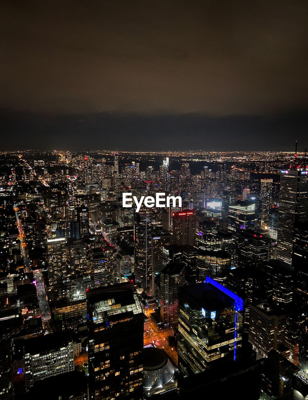 HIGH ANGLE VIEW OF ILLUMINATED MODERN BUILDINGS IN CITY AT NIGHT