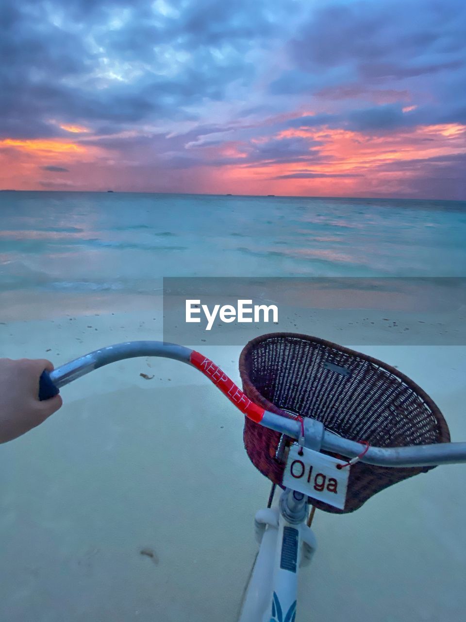 MAN HOLDING UMBRELLA AGAINST SEA DURING SUNSET