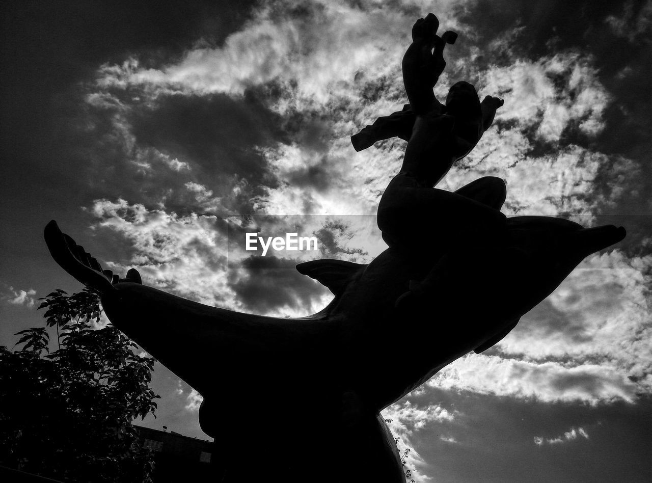 LOW ANGLE VIEW OF STATUE OF LIBERTY AGAINST CLOUDY SKY