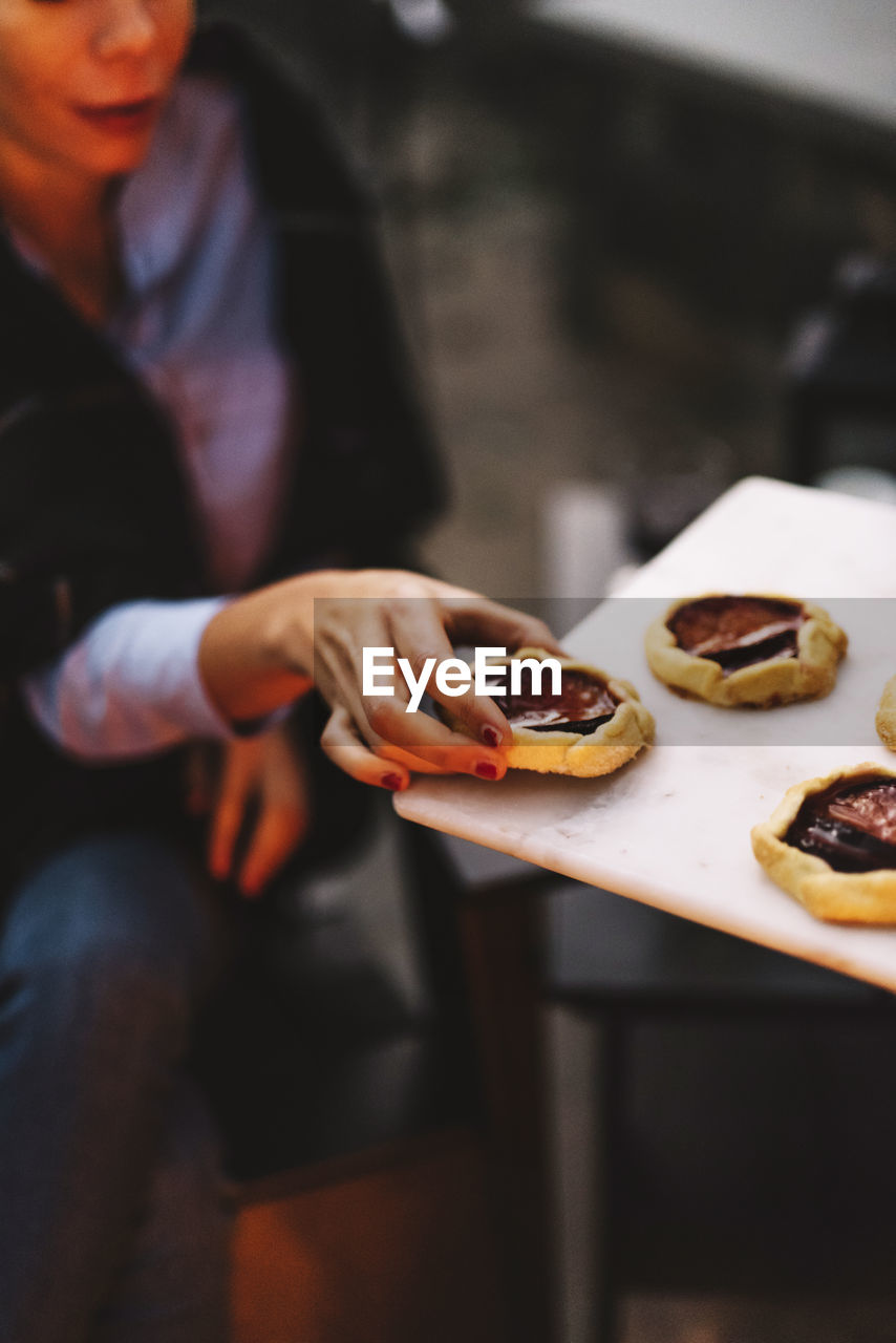 Woman taking rustic plum tart from serving tray