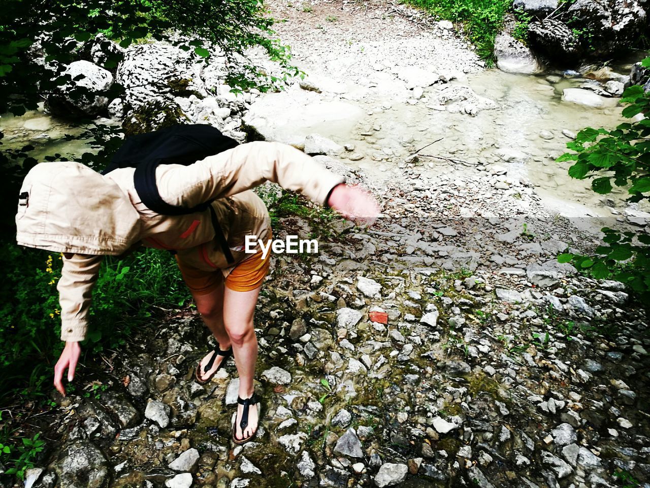 High angle view of woman wearing hooded shirt walking on rocks in forest