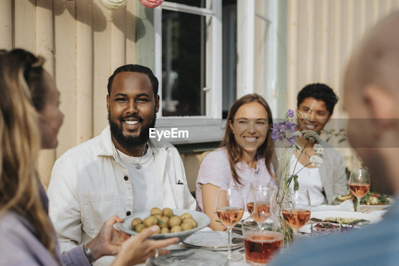 Woman serving baby potatoes to male and female friends during dinner party at cafe