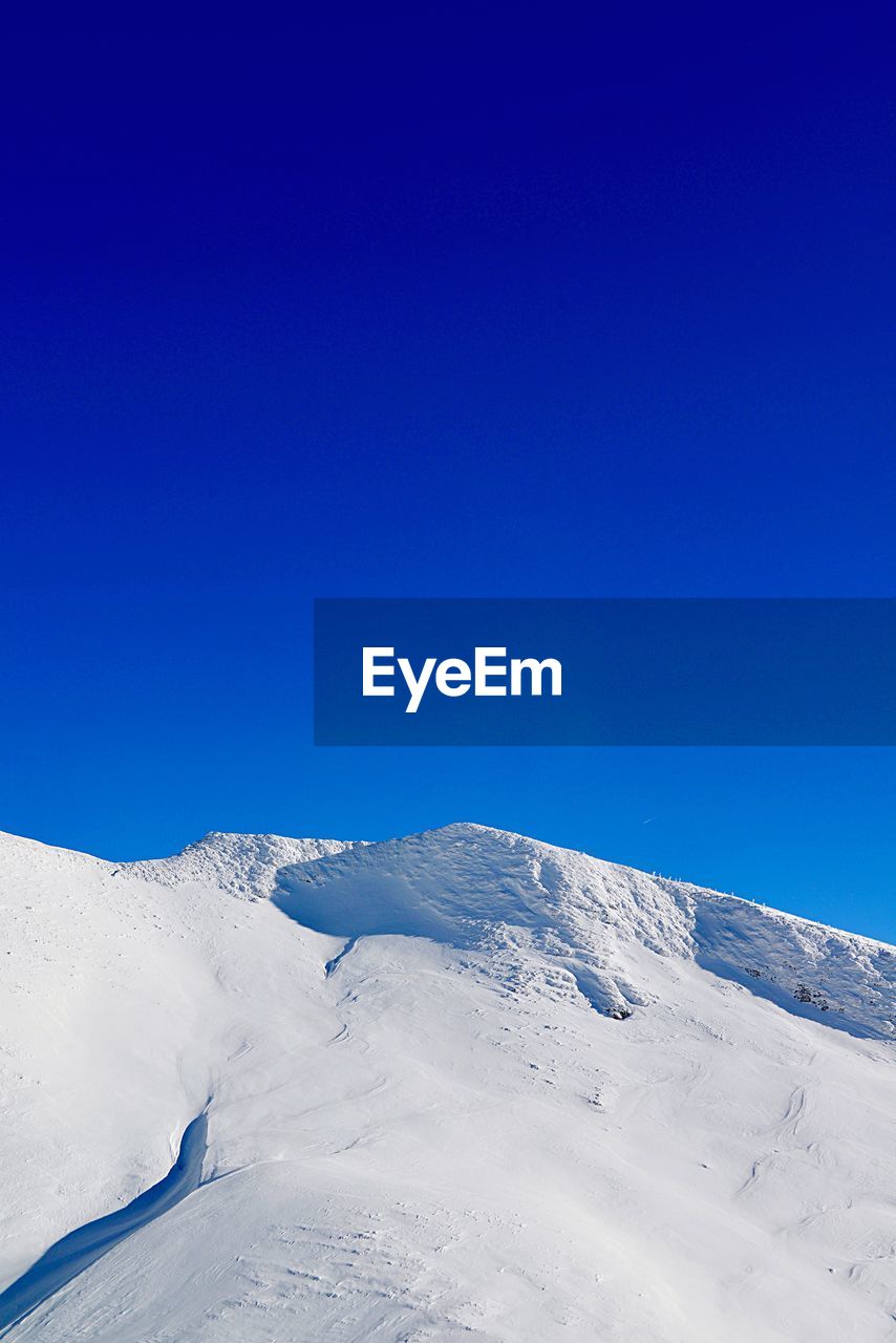 Scenic view of snowcapped mountains against clear blue sky