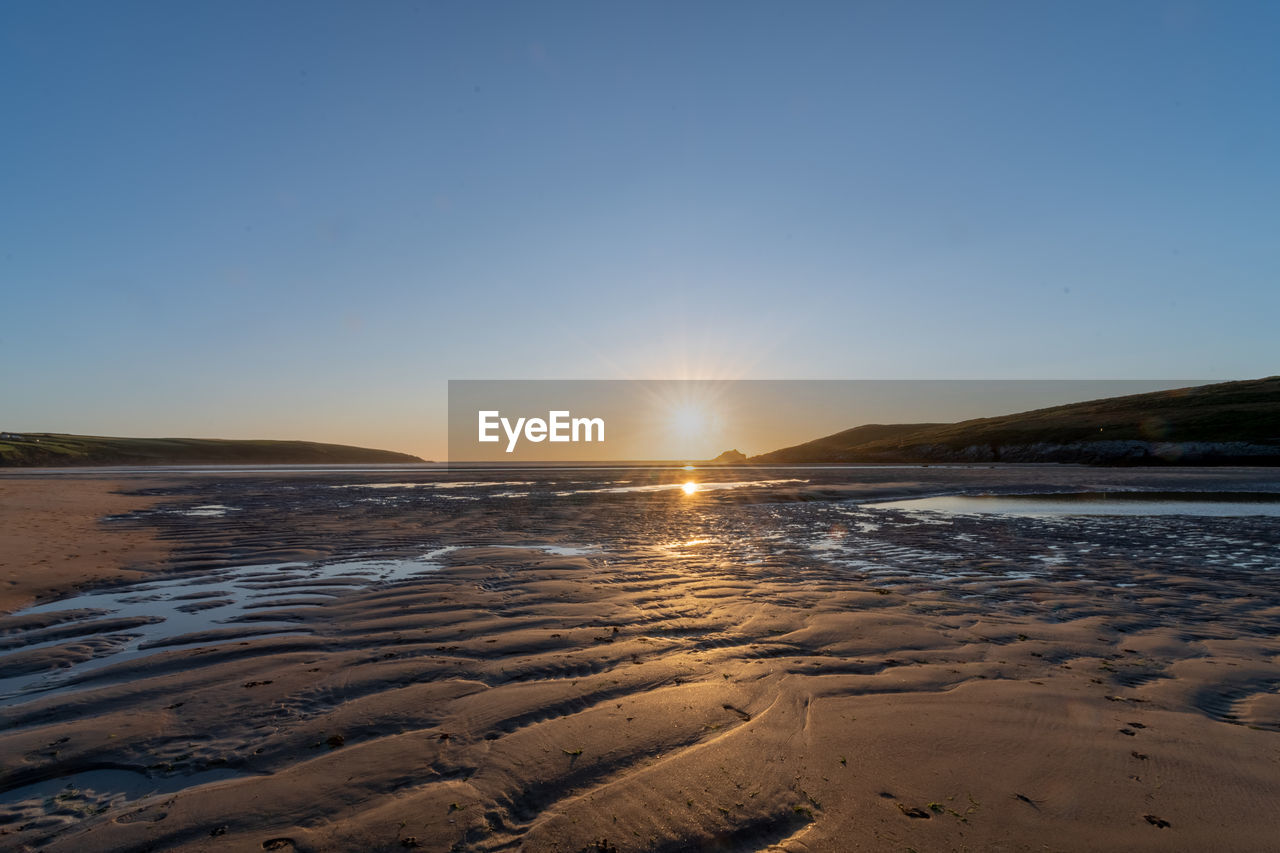 Landscape photo of the sun setting over crantock beach in cornwall