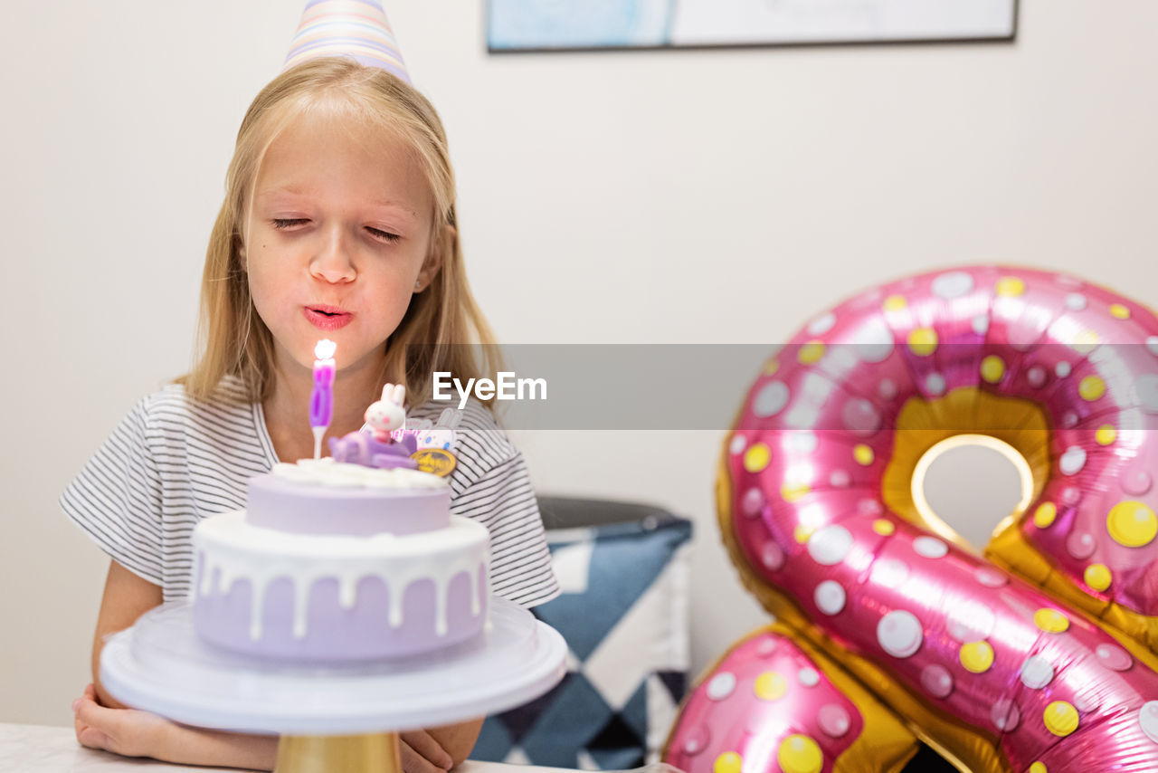 Cheerful girl sitting by balloon during birthday