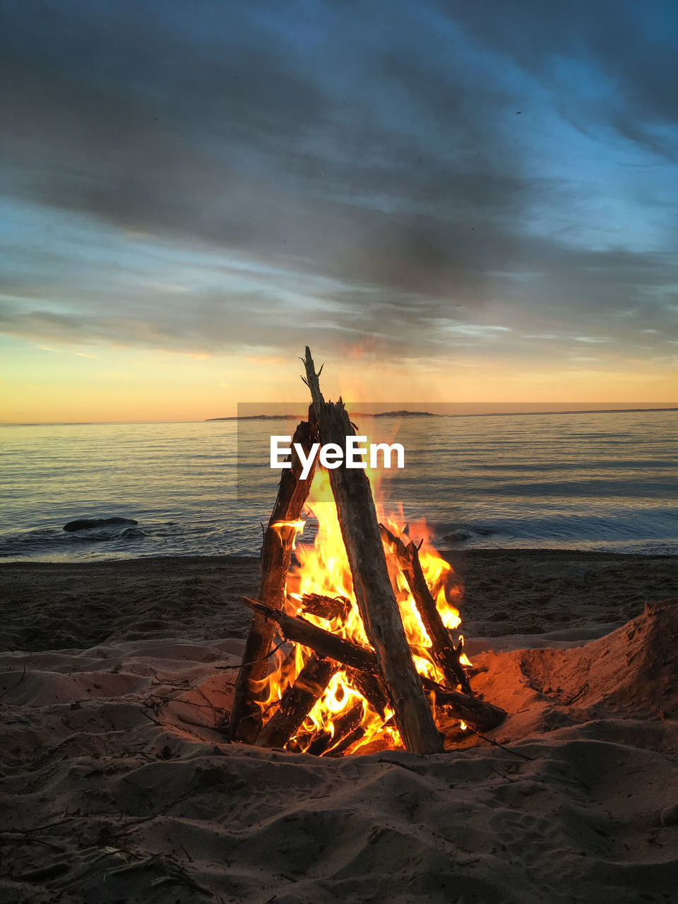 Bonfire on beach against sky during sunset