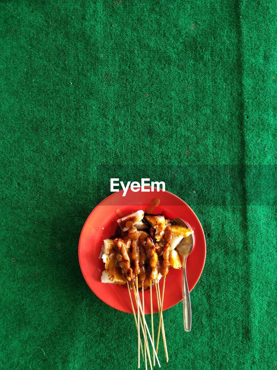 Chicken satay on a green carpet background