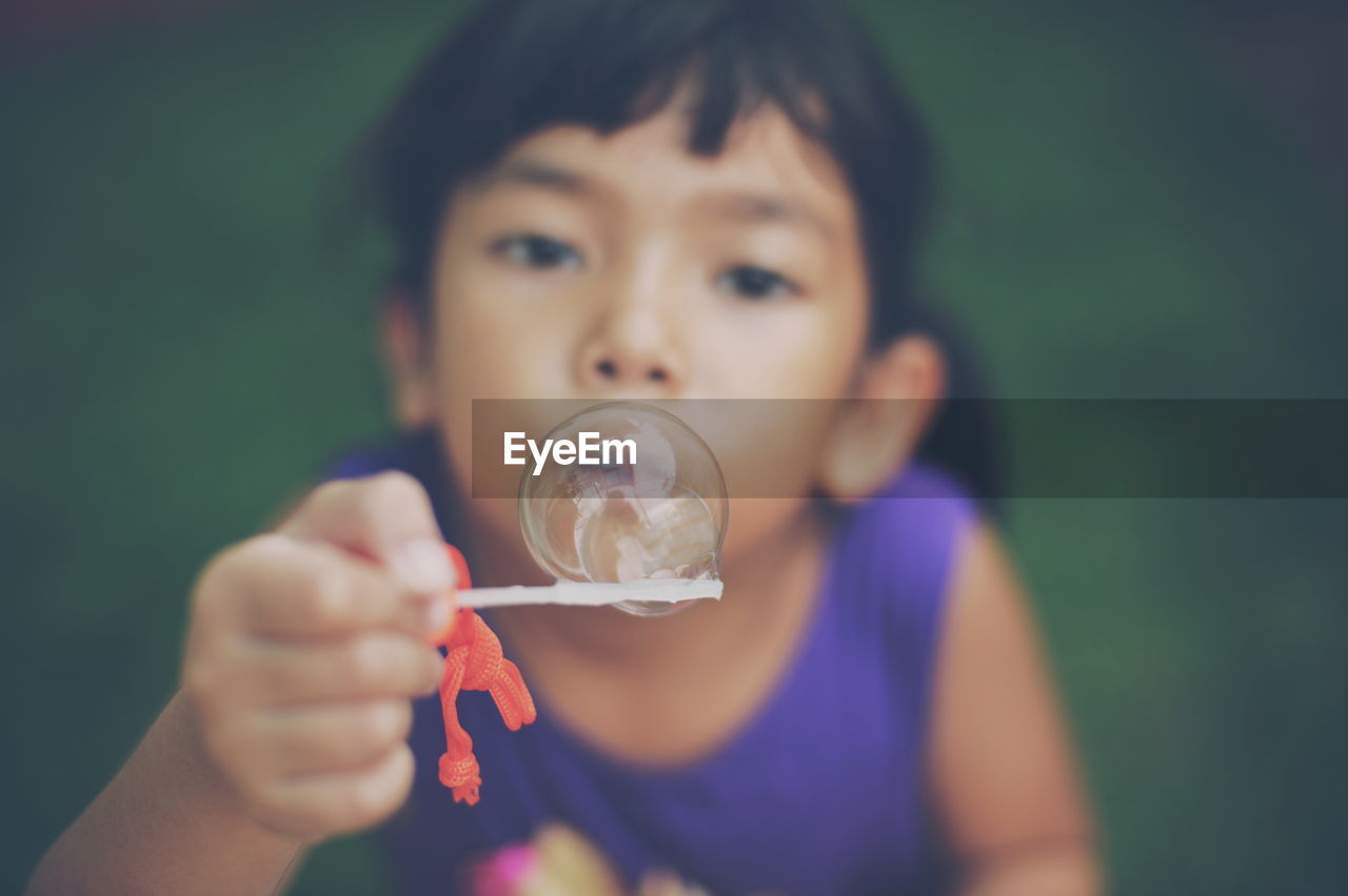 Close-up of girl holding bubble on wand