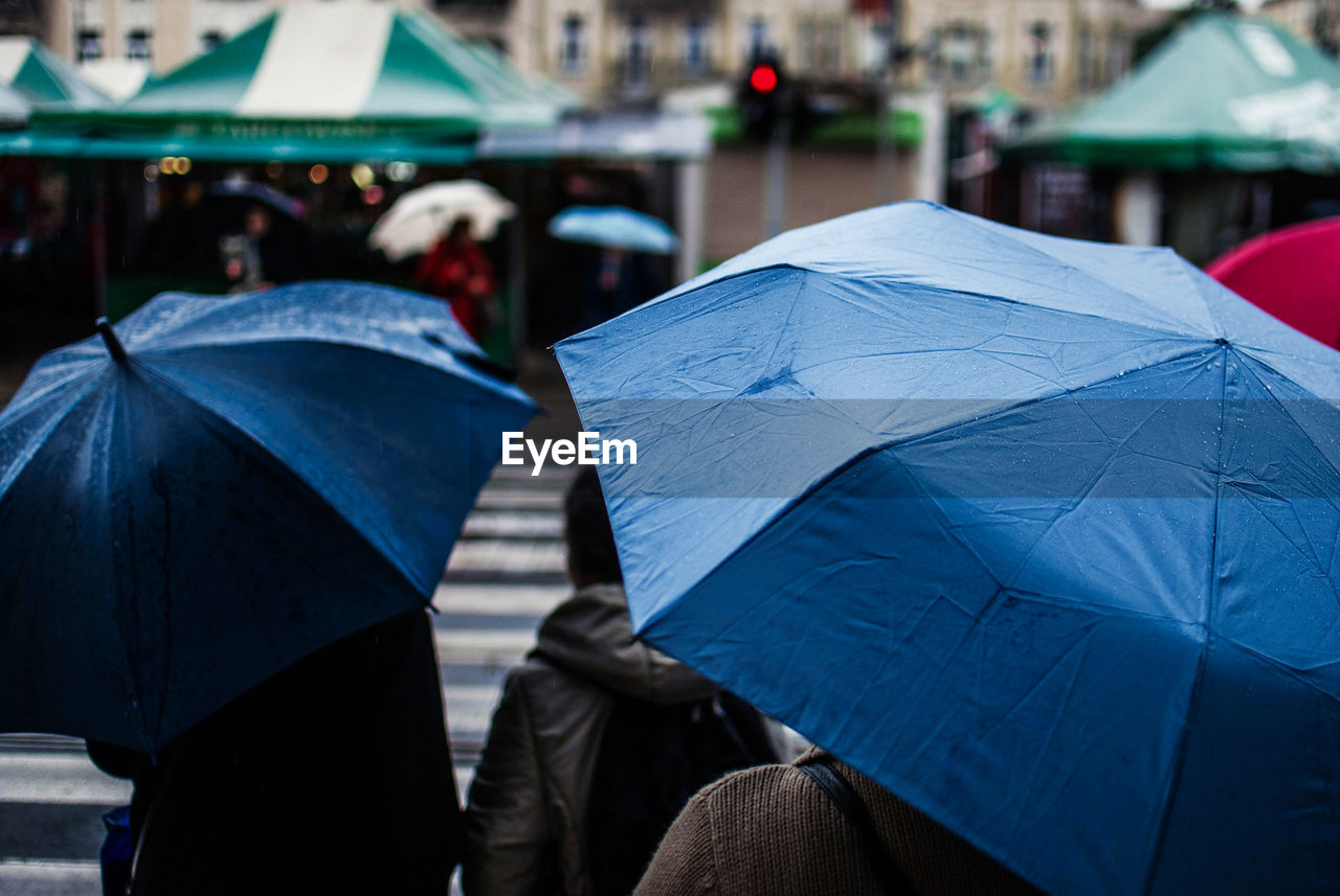 People with umbrellas on street in city during rainy season