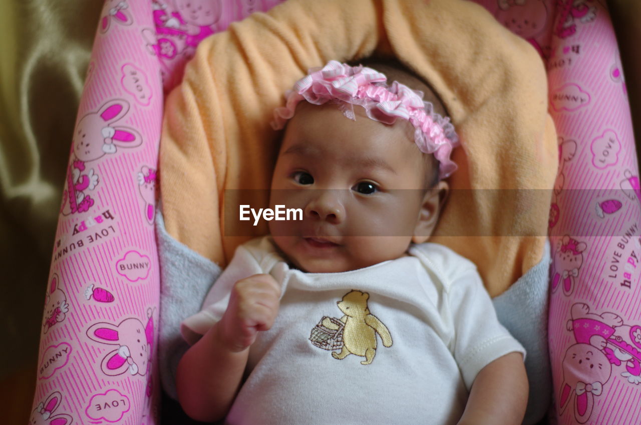 Portrait of cute baby girl lying on bed at home
