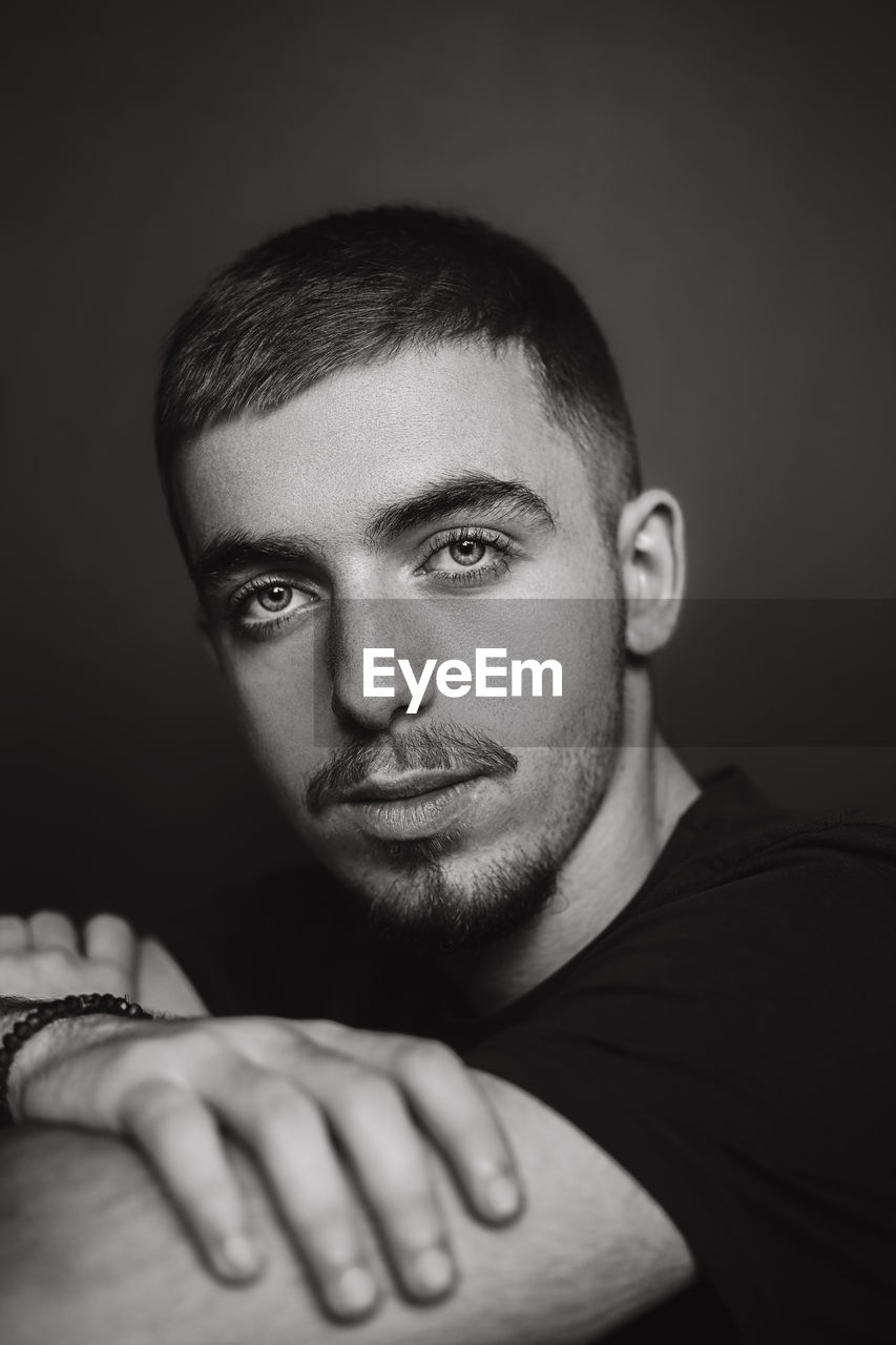 Portrait of young man against black background