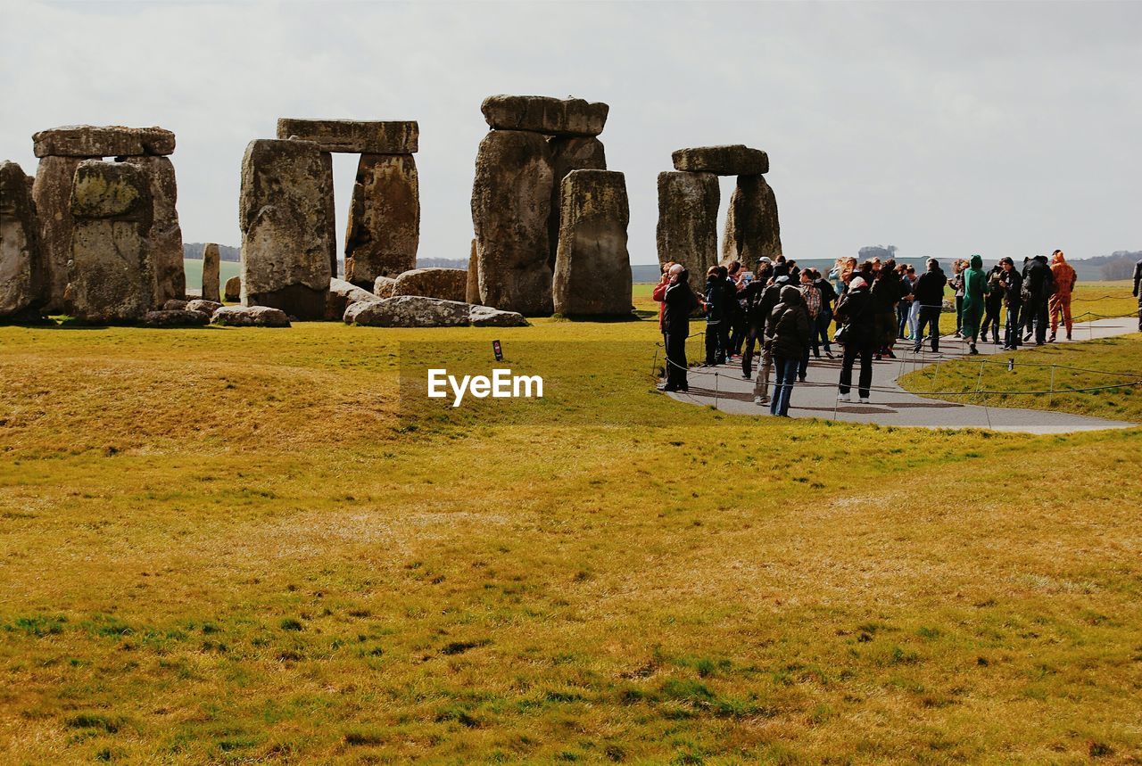 Tourist looking at stonehenge against sky