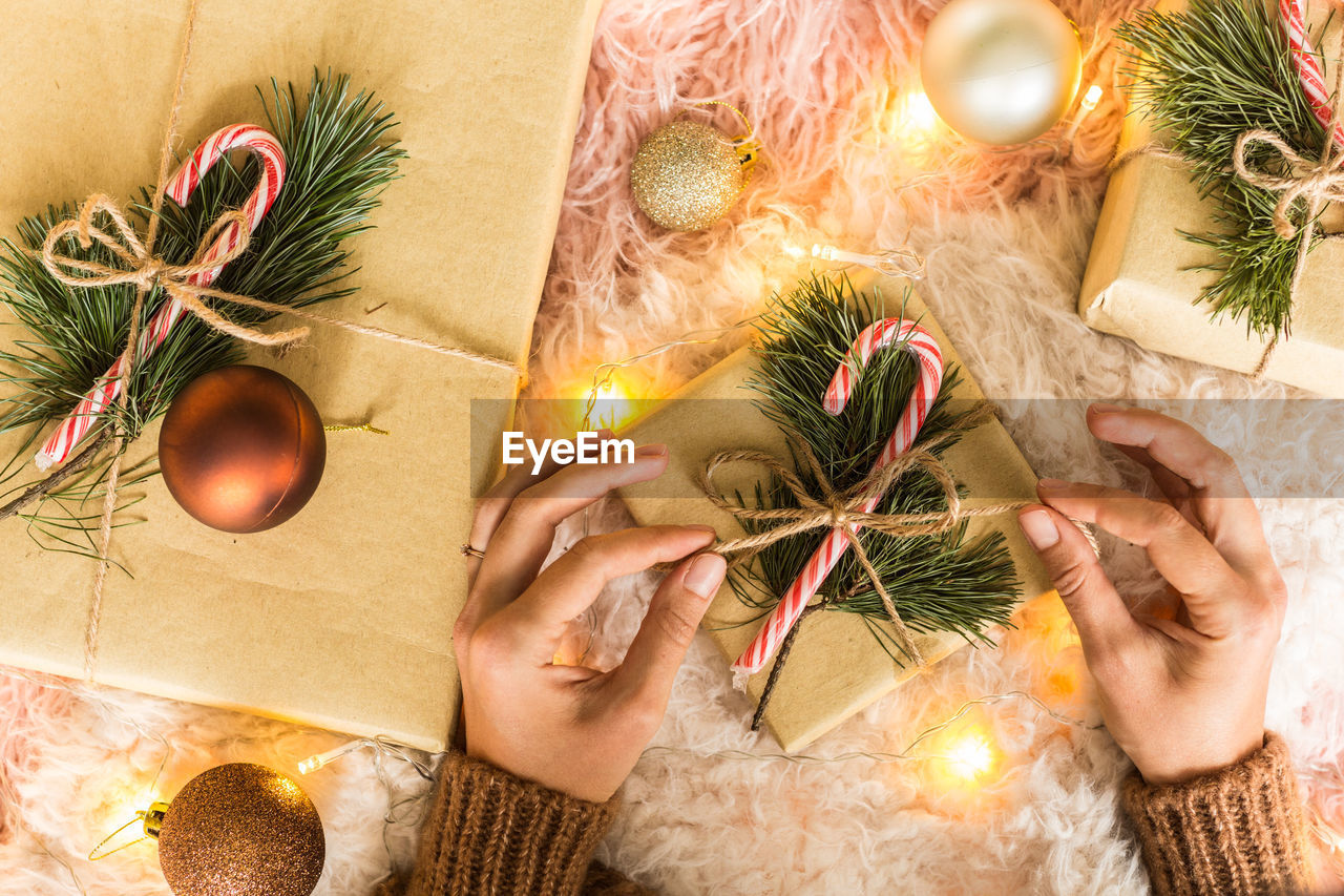 cropped hands of woman holding christmas decorations on table