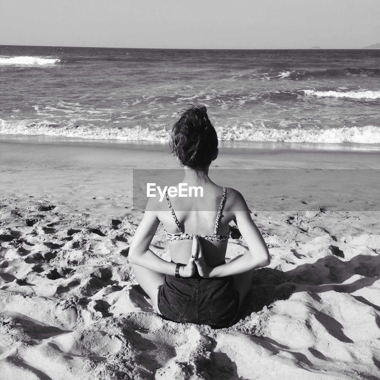 Rear view of woman practicing pashchima namaskarasana position on beach