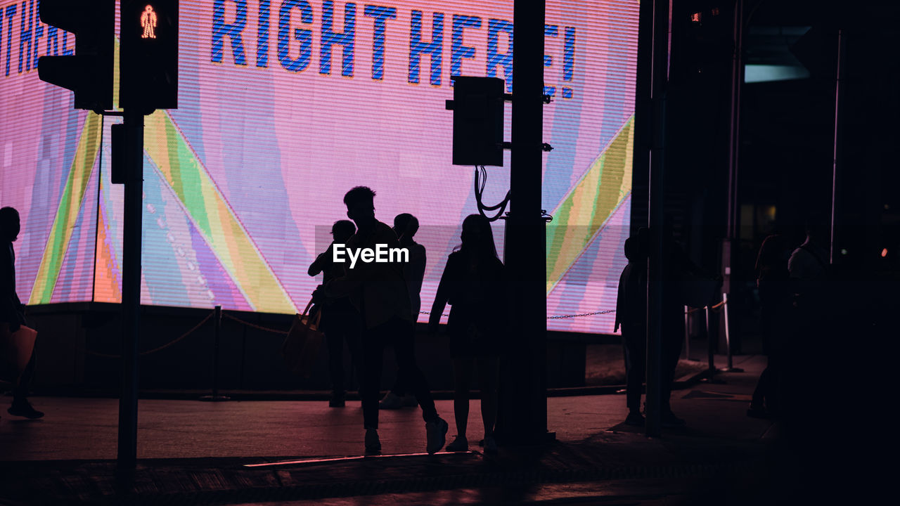 SILHOUETTE PEOPLE STANDING AGAINST ILLUMINATED STAGE