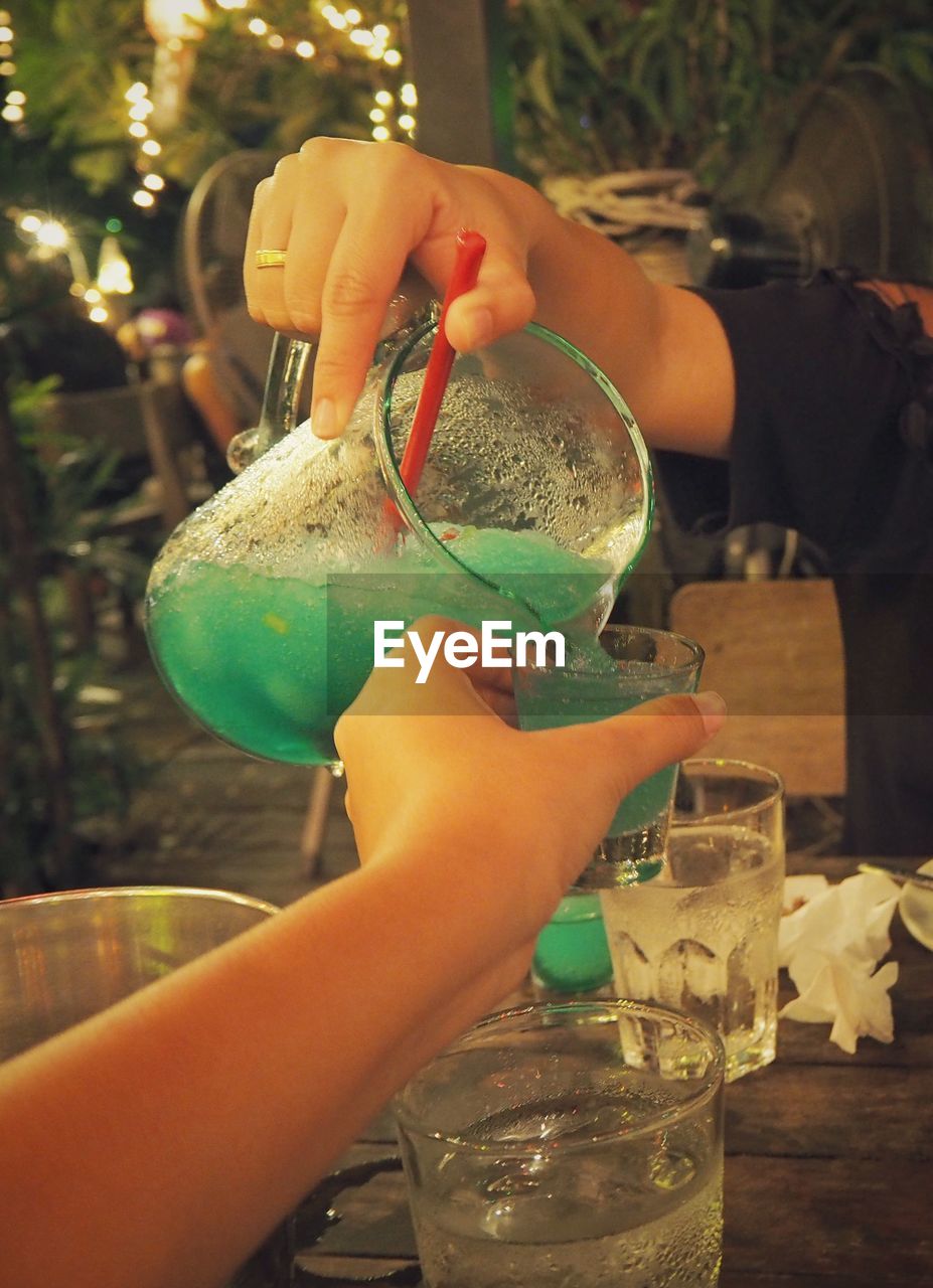 Cropped hand pouring drink for person