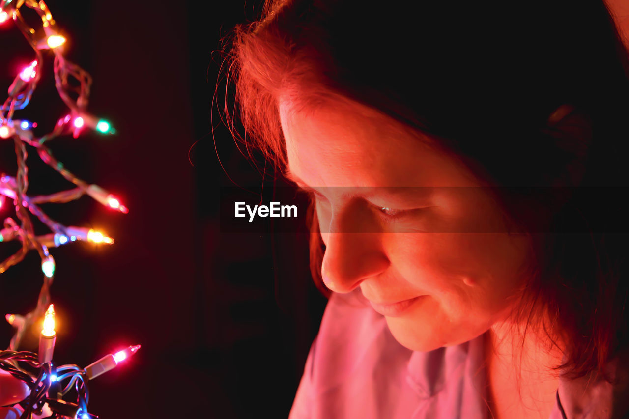 CLOSE-UP PORTRAIT OF WOMAN IN ILLUMINATED CHRISTMAS LIGHTS