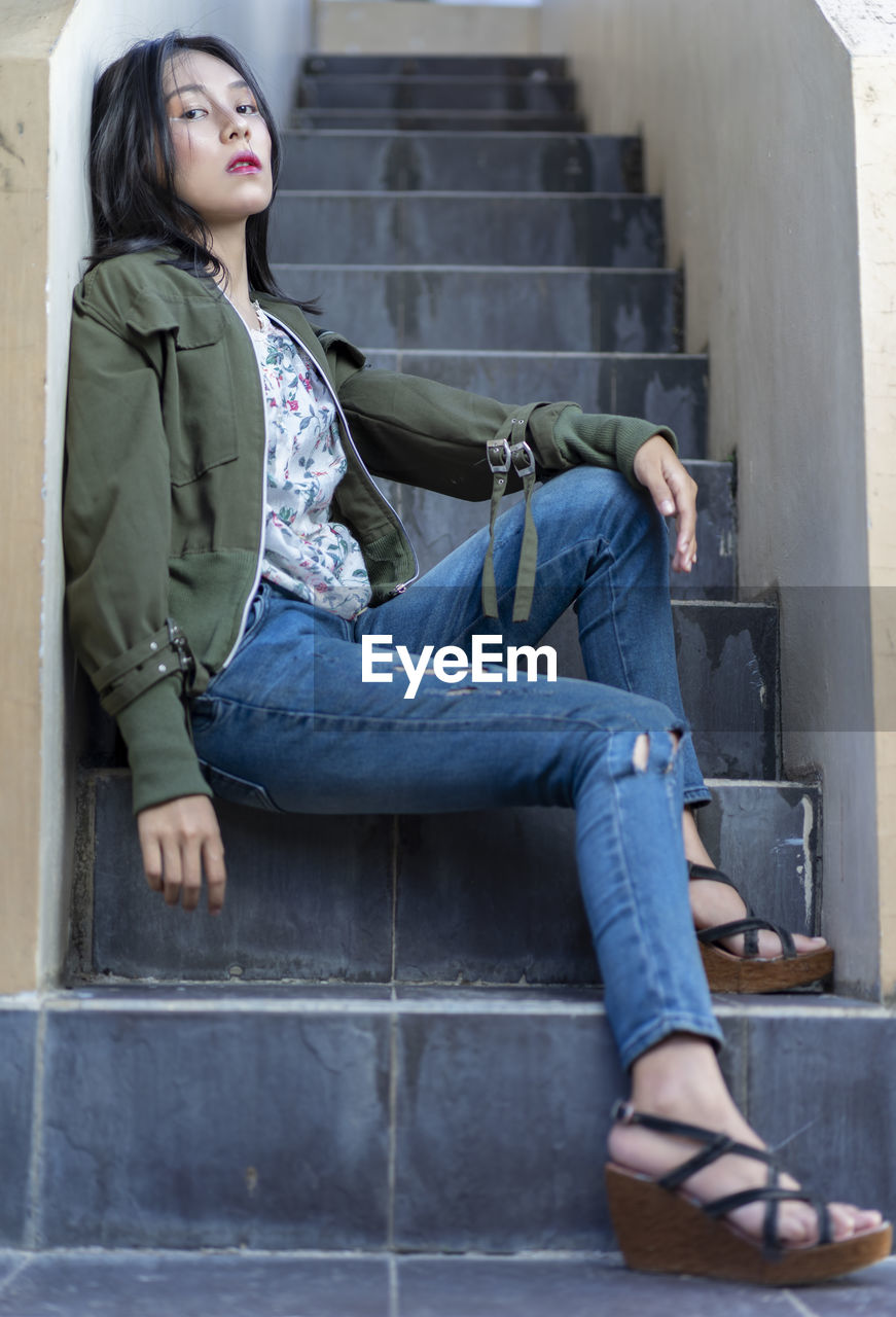 Full length of woman sitting on staircase