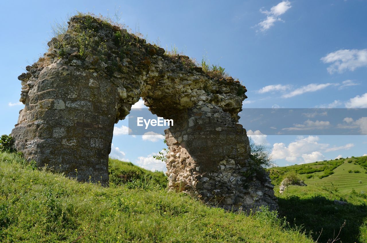 Old ruin on grassy landscape against sky