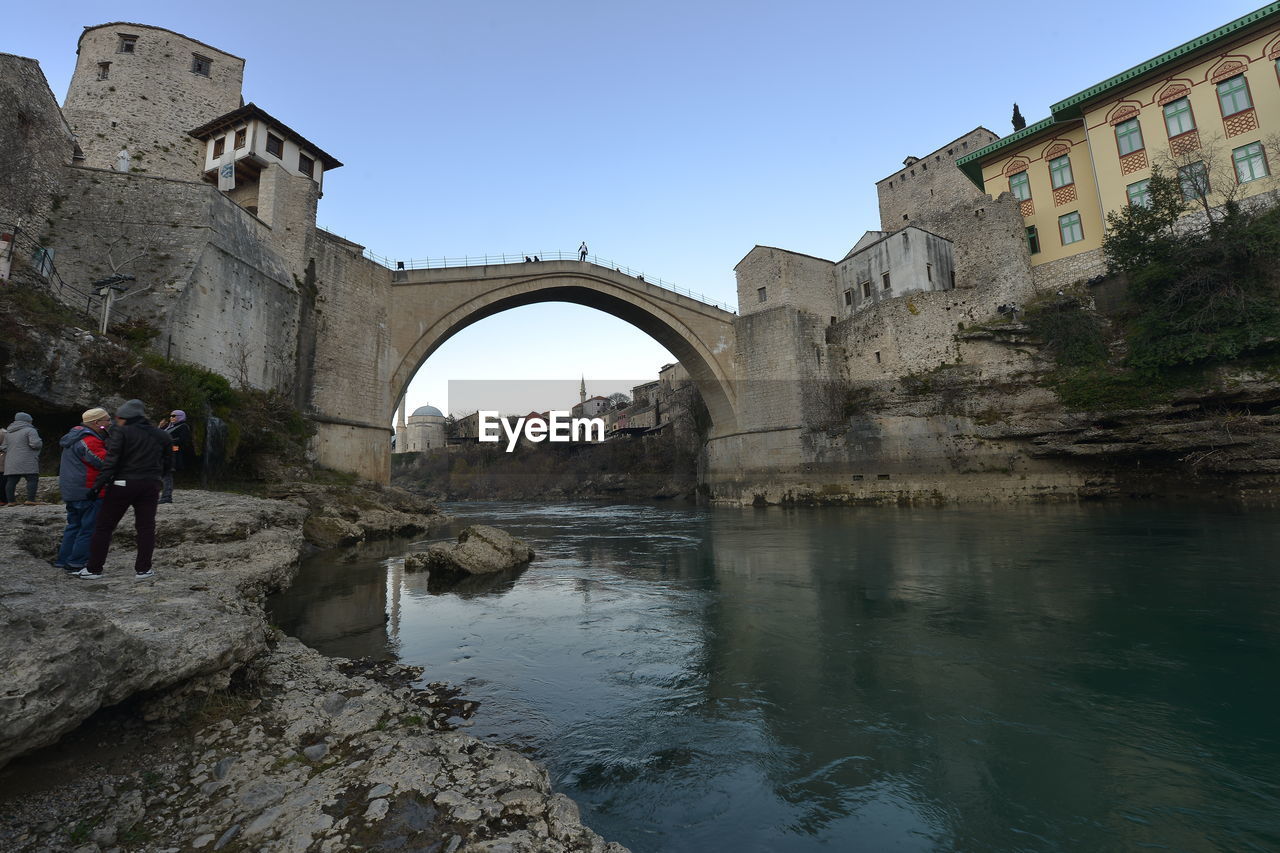 Mostar bridge. people at historic building against clear sky