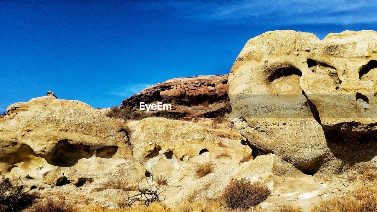 LOW ANGLE VIEW OF ROCK FORMATION AGAINST BLUE SKY