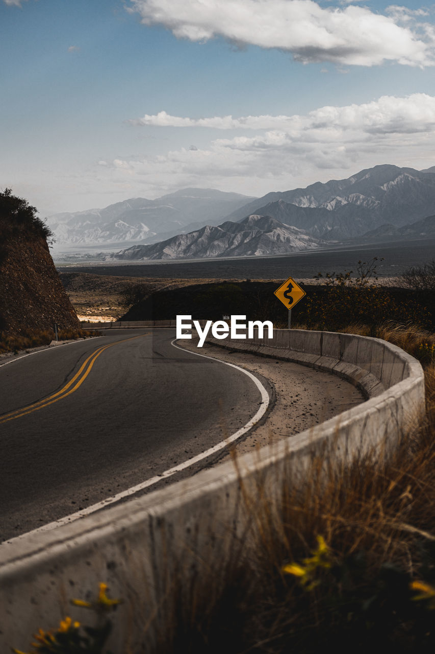 Road leading towards mountains against sky