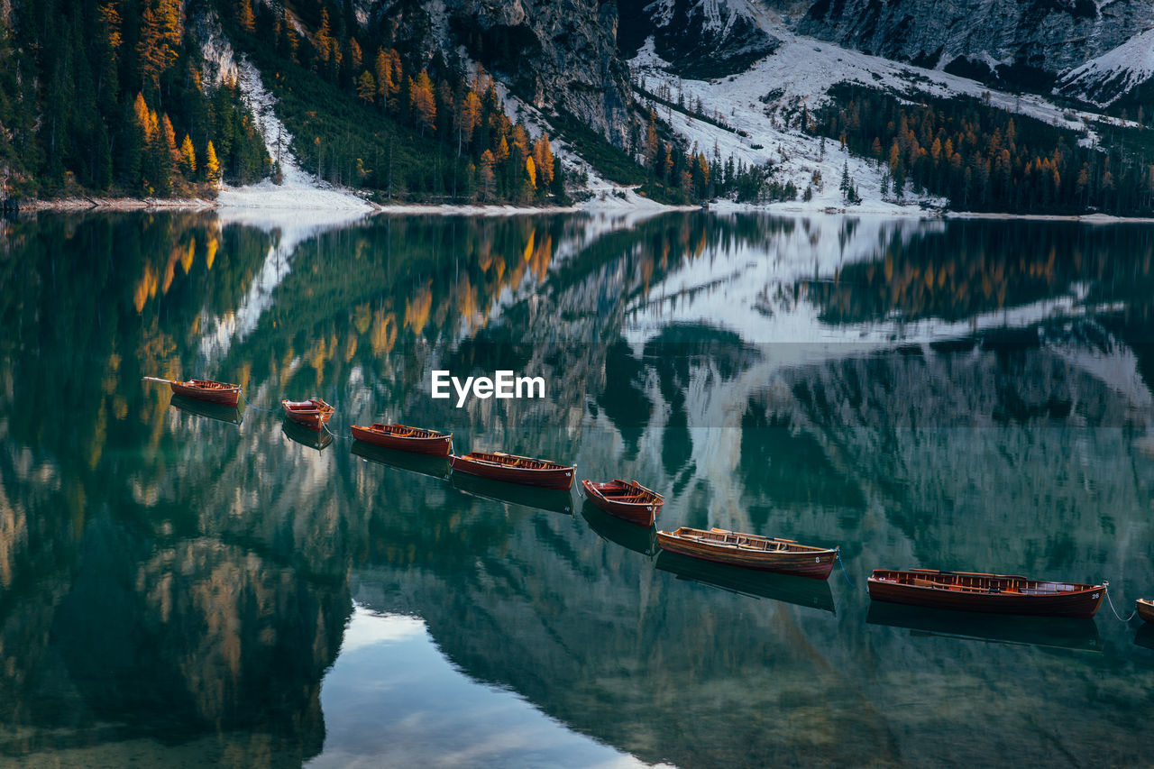 Boats in lake against snowcapped mountains