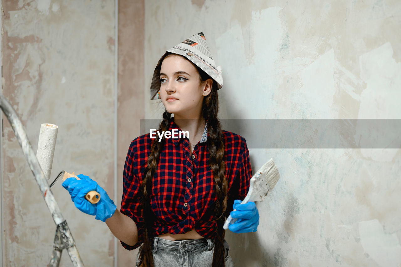 Portrait of young woman standing against wall.  painter works occupation 