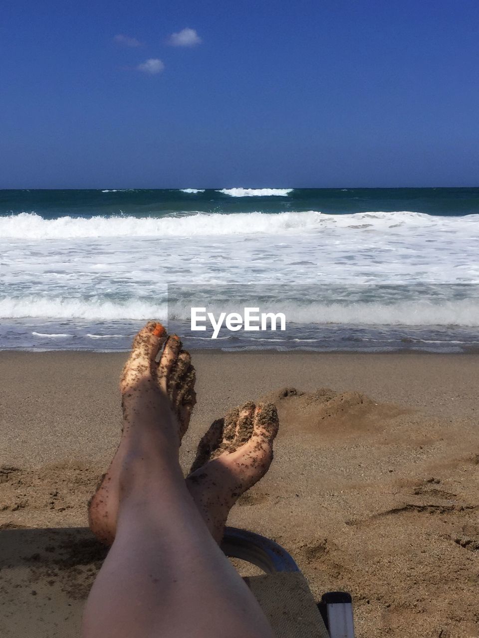 Low section of women sitting on beach