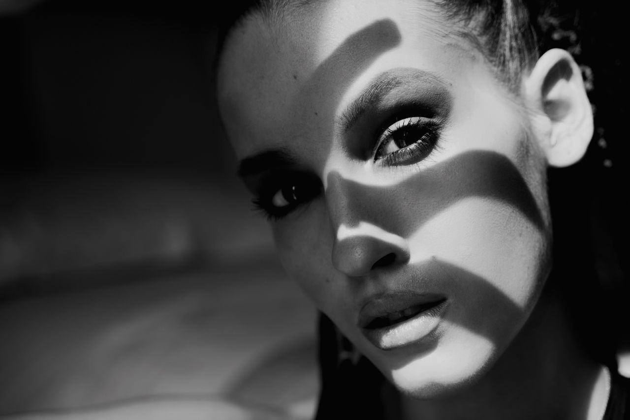 Close-up portrait of young woman in black and white with the shadow on their face